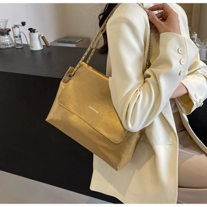 Detail of metallic gold chain shoulder bag with Fashion Bags print on white blazer