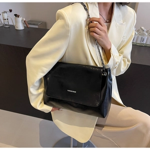 Retro black glossy tote bag with silver chain strap shown in a modern cafe setting