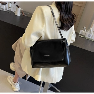 Detailed view of black leather chain crossbody bag with white FASHION BAGS lettering