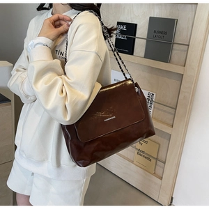 Detail of a dark caramel leather crossbody bag with silver chain and Fashion Bags logo