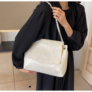 Close-up of cream crossbody bag featuring a crinkled leather texture and silver chain strap