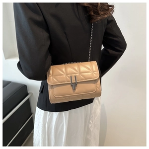 Detail of beige quilted faux leather bag featuring a gray metal buckle and chain strap