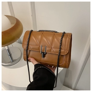 Close-up of caramel quilted crossbody bag with metal chain strap and twist-lock closure