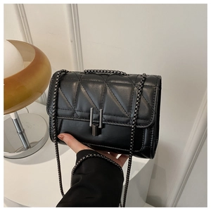 Detailed view of black quilted crossbody bag with diamond stitching and metal chain strap