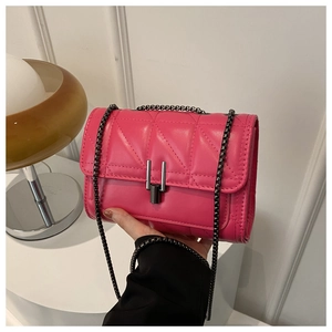 Gros plan du sac à main en cuir matelassé rose vif avec chaîne en métal et fermoir en U