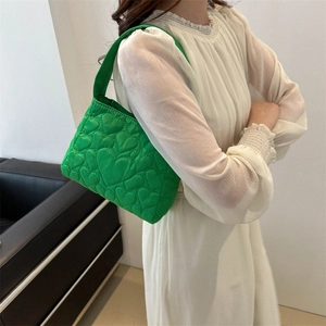 Sac à main matelassé vert vif à motif cœurs porté par un mannequin de profil
