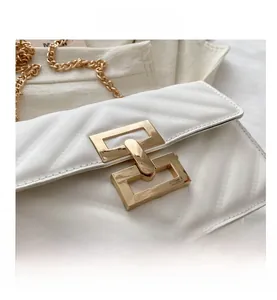 Close-up of golden rectangular lock and V-quilted white leather on luxury handbag