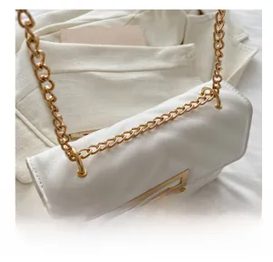 Close-up of the durable gold metal chain link on a white leather shoulder bag