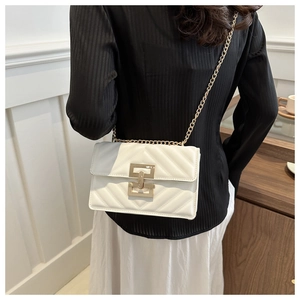 Detailed view of white quilted crossbody bag with gold chain strap and metal lock