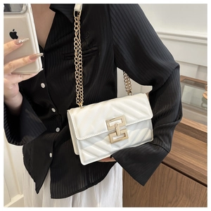 Close-up of white quilted leather bag with elegant gold interlocking metal clasp and chain