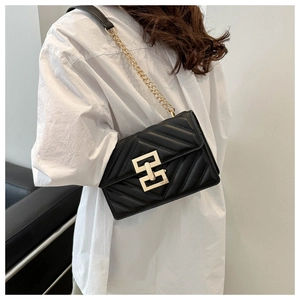 Detail of black quilted shoulder bag with gold chain strap and geometric metal lock