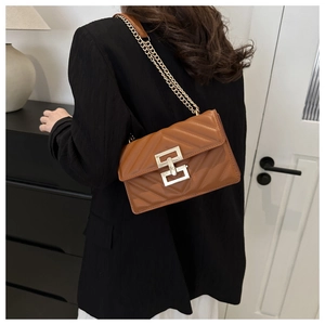 Close-up of brown V-quilted small square bag with gold chain strap on model's shoulder