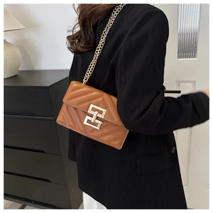 Detail of a brown chevron quilted crossbody bag featuring a gold chain and geometric clasp