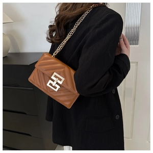 Detail of vintage brown leather crossbody bag with V-chevron quilting and gold chain strap