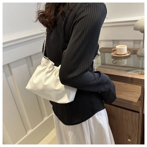 Detail showing the white pleated cloud bag with a silver chain strap on a model