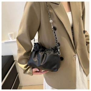 Detail of black pleated cloud bag with silver chain strap and hollow metal ball charm