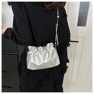 Macro shot of silver pleated cloud bag featuring delicate chain and metallic finish
