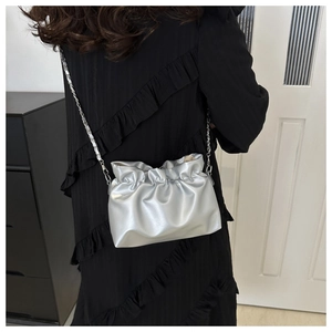 Detail of silver metallic cloud bag with gathered pleats and woven chain strap