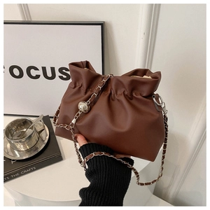 Détail d'un sac bourse en cuir marron avec une fine chaîne argentée et perle en métal