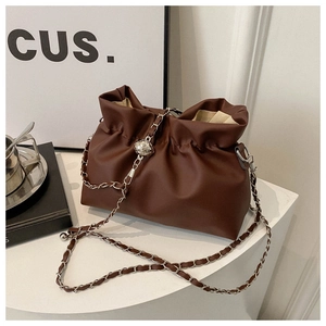 Close-up of brown pleated cloud bag with silver chain and quilted metal ball detail