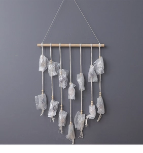 Detail of bohemian wall hanging featuring natural wood rod and cotton rope with beads