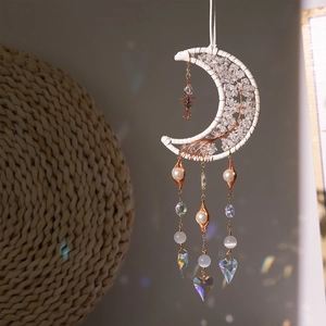Macro shot of crescent moon suncatcher with raw crystals and heart prism reflecting rainbow