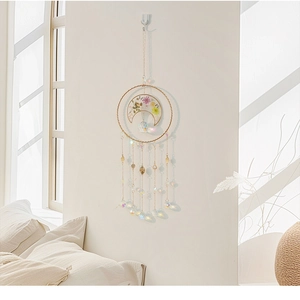 Detail of moon suncatcher with crystal prisms and gold moon frame hanging on a wall