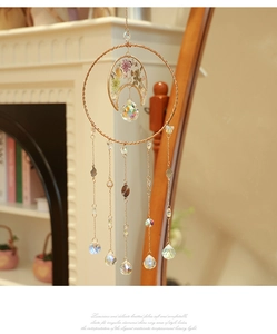 Detail of moon-shaped crystal dream catcher with dried flowers and golden leaf pendants
