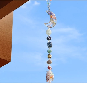 Hanging 7 chakra raw crystals with metal moon frame and woven rope against blue sky
