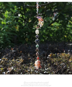 Macro shot of seven raw chakra stones wrapped in mesh on a moon-shaped tree of life