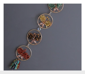 Close-up of colorful natural crystal butterfly suncatcher with golden wire weaving details