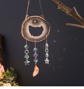 Detail of natural agate suncatcher with crystals and raw gemstone hanging on a branch