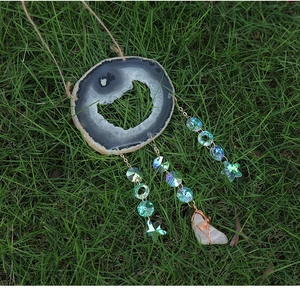 Macro view of natural agate slice wind chime with faceted crystal beads and star pendants
