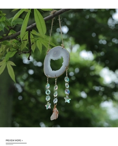 Macro detail of natural agate slice wind chime with colorful crystals on a tree branch