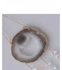 Macro detail of natural agate slice wind chime with golden chain and faceted glass beads