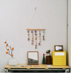 Handmade wall decor with natural crystals and raw stones hanging on a wooden stick