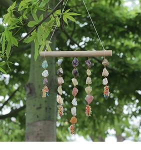 Outdoor close-up of handmade raw crystal stones hanging from a natural wooden stick