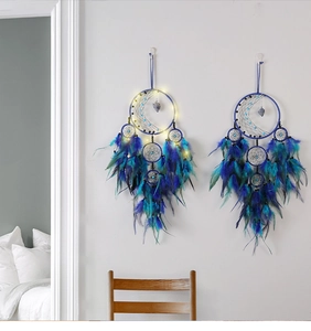 Detail of dream catcher with moon frame, blue feathers and warm LED fairy lights