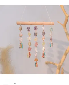 Detail of handcrafted bohemian suncatcher featuring raw crystals on a natural wood rod