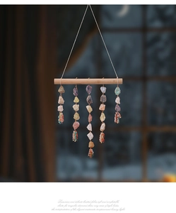Close-up of hand-woven colorful raw crystal stones hanging from a natural wood stick