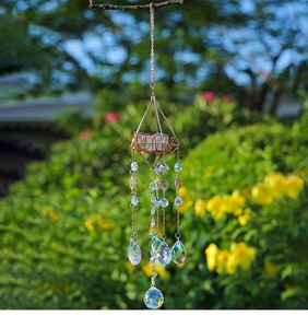 Detail of golden geometric suncatcher with raw stones and crystals hanging in a garden