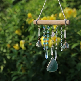 Detail of natural green agate slice and crystal wand hanging on a handmade wind chime