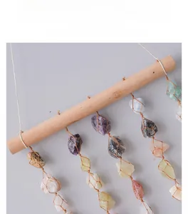 Detail of natural raw crystal stones hanging from a wooden bar with woven mesh