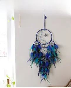 Detail of handmade dreamcatcher featuring blue feathers and crescent moon wall decor