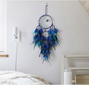 Detail of moon-shaped dream catcher with blue feathers and crystal stone on wall