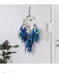 Detail of blue glowing dream catcher with LED moon ring and hanging feathers on white wall