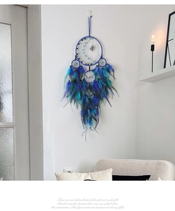 Detail of dream catcher featuring blue feathers and crescent moon on a white wall