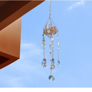 Golden geometric suncatcher with raw crystal and evil eye bead against blue sky