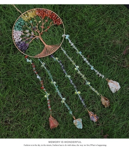 Detail of tree of life wind chime with colorful natural crystals on green grass