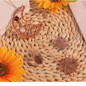 Detail of rose gold wire-wrapped moon pendant with natural purple amethyst clusters